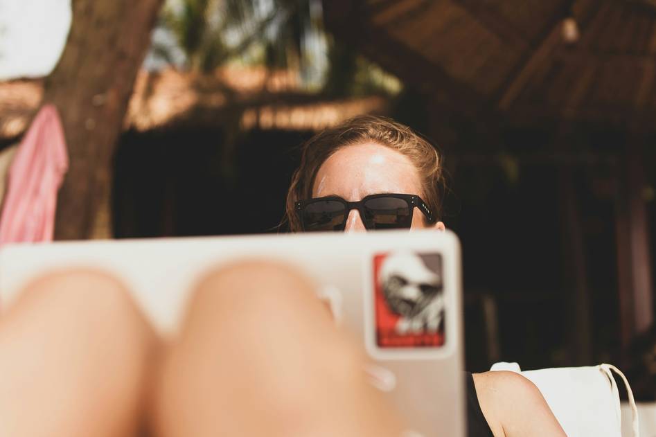 Remote worker typing on laptop overlooking scenic mountain lake at sunrise