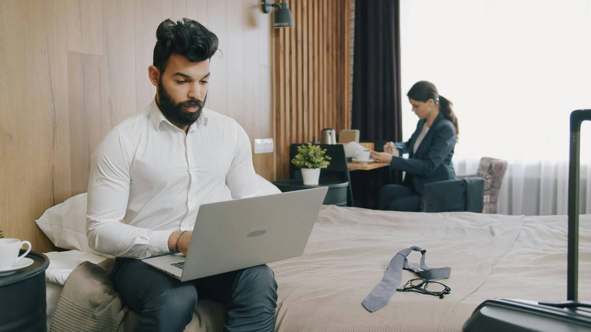 how to work remote and travel: person using laptop in airport lounge with multiple power adapters and SIM cards laid out